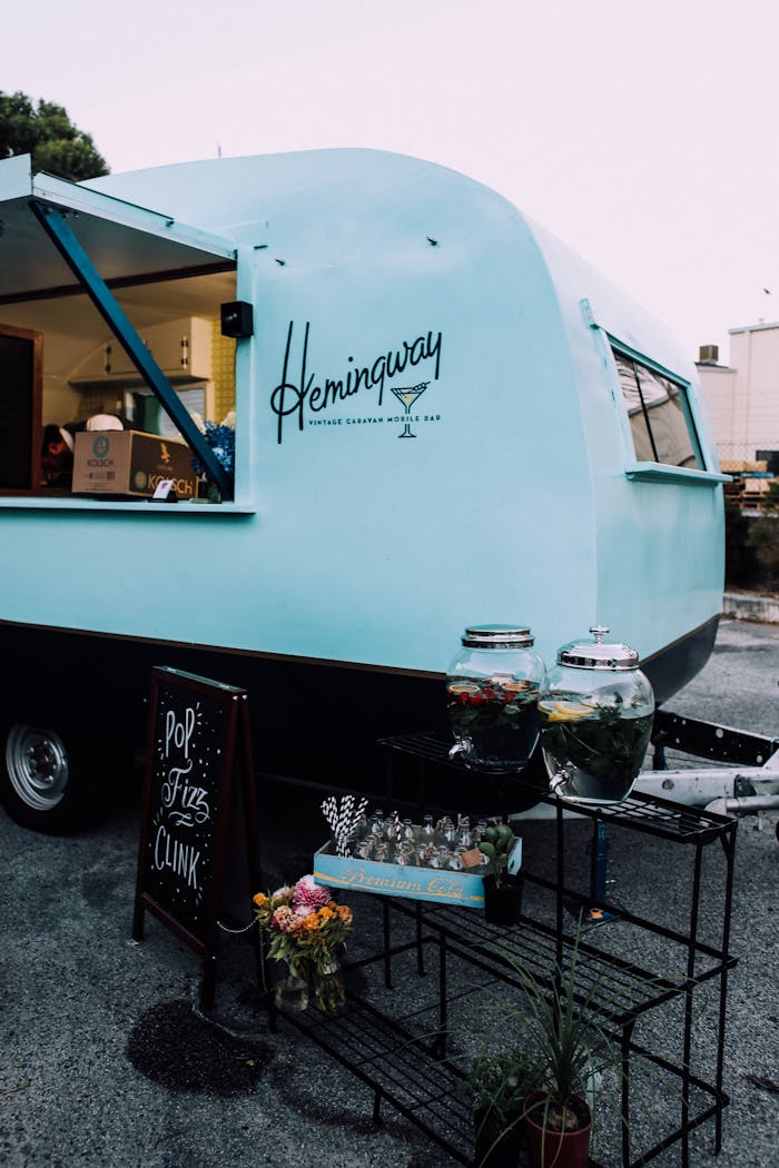 A retro blue food truck in a city street serving beverages with stylish outdoor decor.