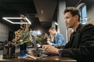 Adults working in a modern office with Christmas decorations, using laptops.