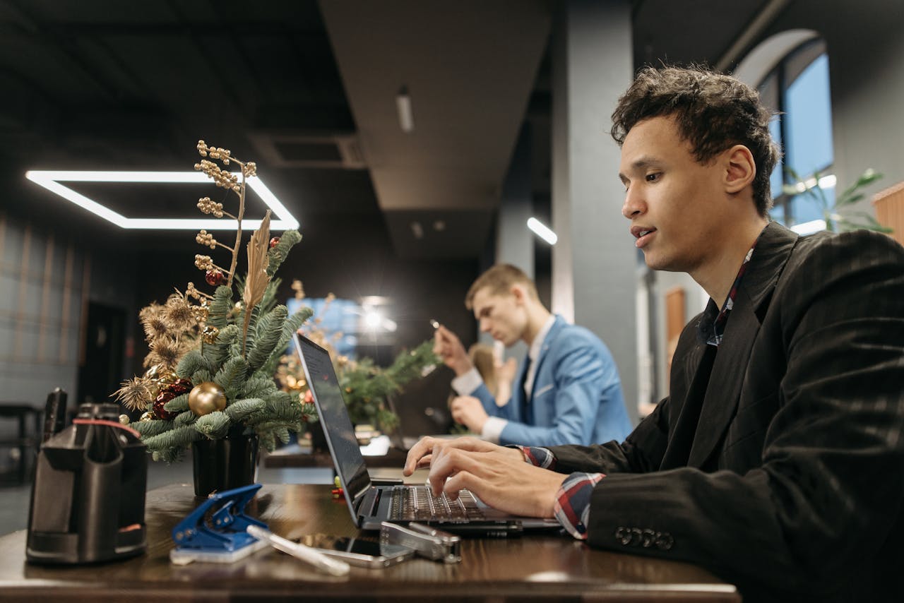 Adults working in a modern office with Christmas decorations, using laptops.